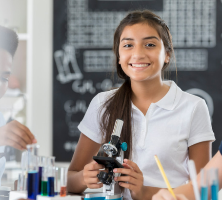 Menina sorrindo ao microscópio em laboratório escolar